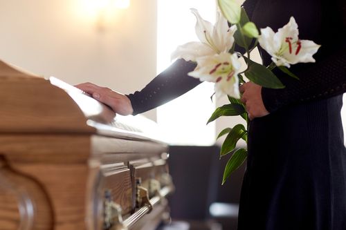 Image is of a women standing in front of a casket at a funeral concept of Clemmons wrongful death lawyer