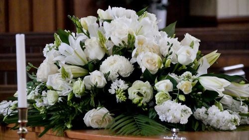 Image is of white flowers on top of a casket, concept of Lewisville wrongful death lawyer
