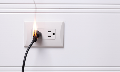 Image is of a plug in an outlet on fire concept of Winston Salem product liability lawyer