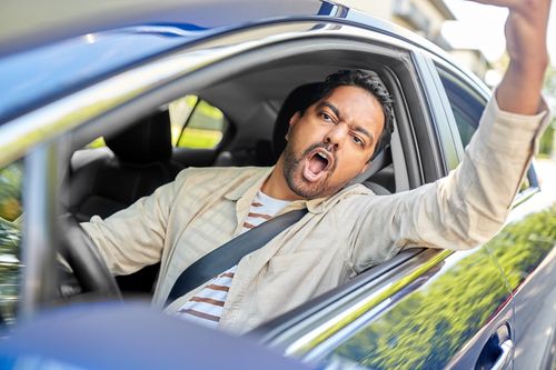 Image is of a man yelling out of his car window due to road rage, concept of Winston Salem reckless driving lawyer