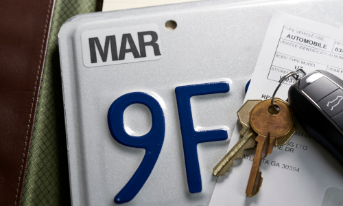 Image is of a set of car keys, a license plate, and registration, concept of Winston Salem suspended license lawyer